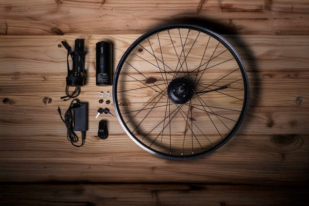 A close-up of an electric bike conversion kit with tools and a regular bicycle in the background.